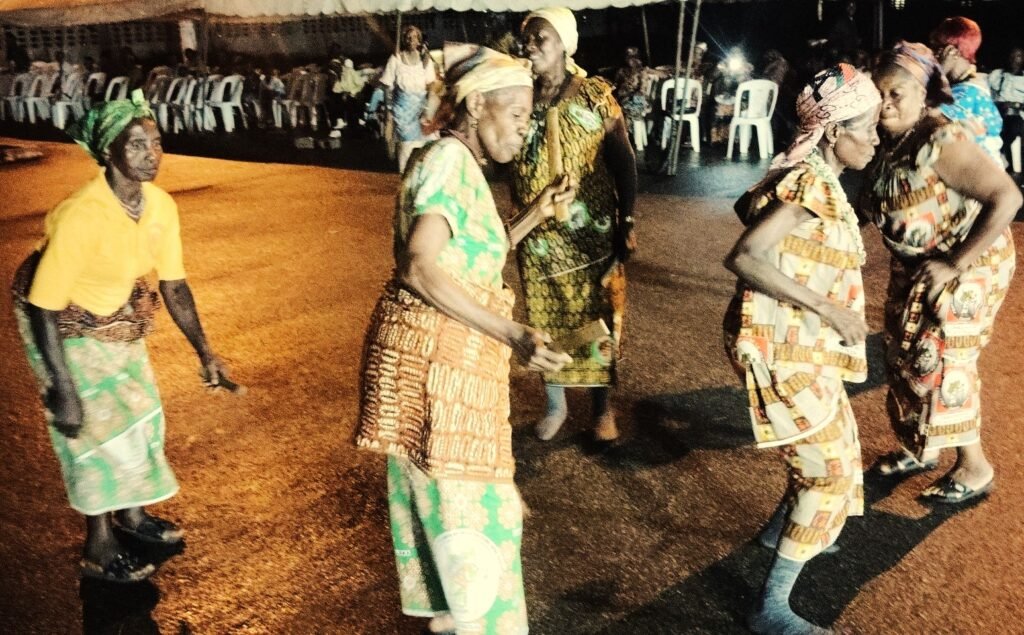 Image montrant un groupe de femmes vêtues d’habits traditionnels ivoiriens, en train de danser lors d’une fête communautaire à Grand-Lahou.