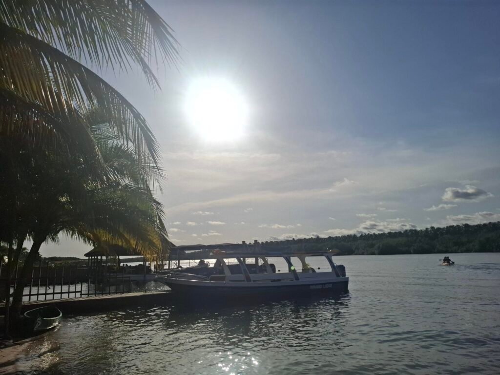 Coucher de soleil éclatant sur la lagune Ébrié, vu depuis l’Île Boulay, illustrant la beauté naturelle et l’atmosphère sereine de la destination.