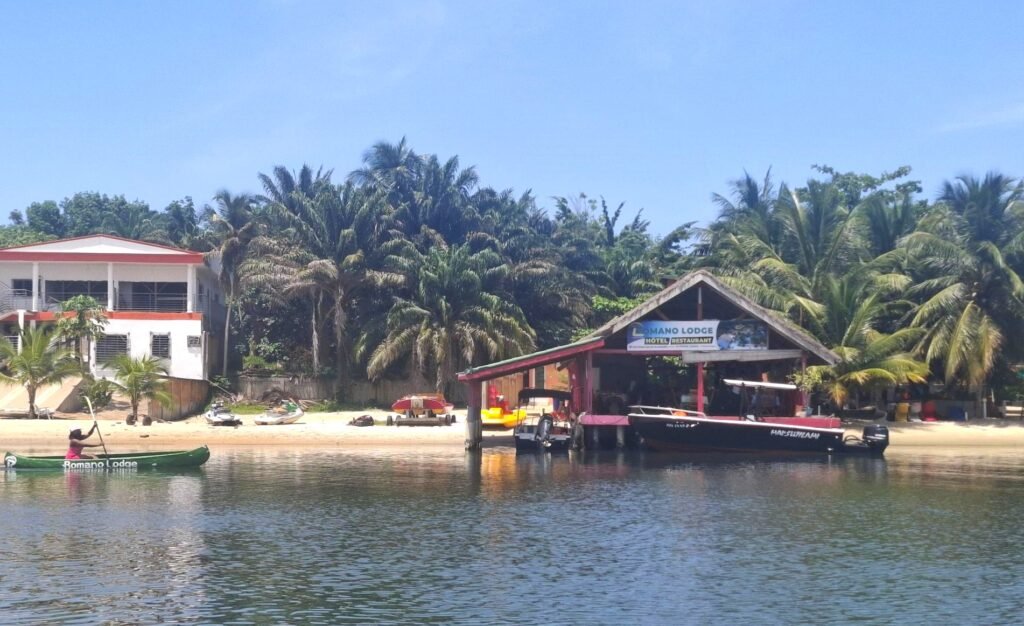 Entrée principale du Romano Lodge sur l’Île Boulay, encadrée par une végétation tropicale et évoquant une ambiance chaleureuse et accueillante.