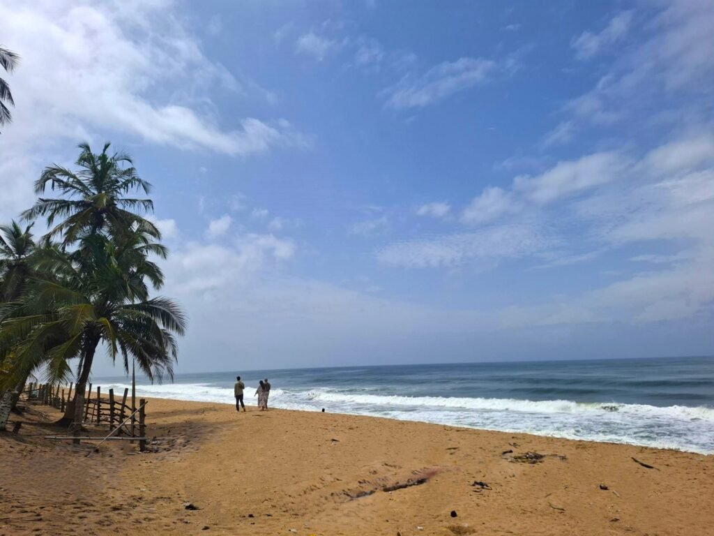 Plage de Jacqueville en Côte d’Ivoire, bordée de sable doré et de cocotiers.