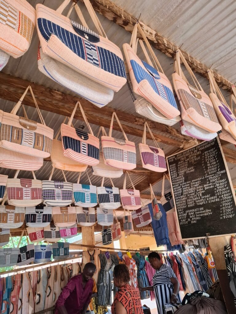 Sacs artisanaux en tissu coloré, soigneusement fabriqués par les tisserands du Marché de Waraniéné, exposés sur un étal de vente.