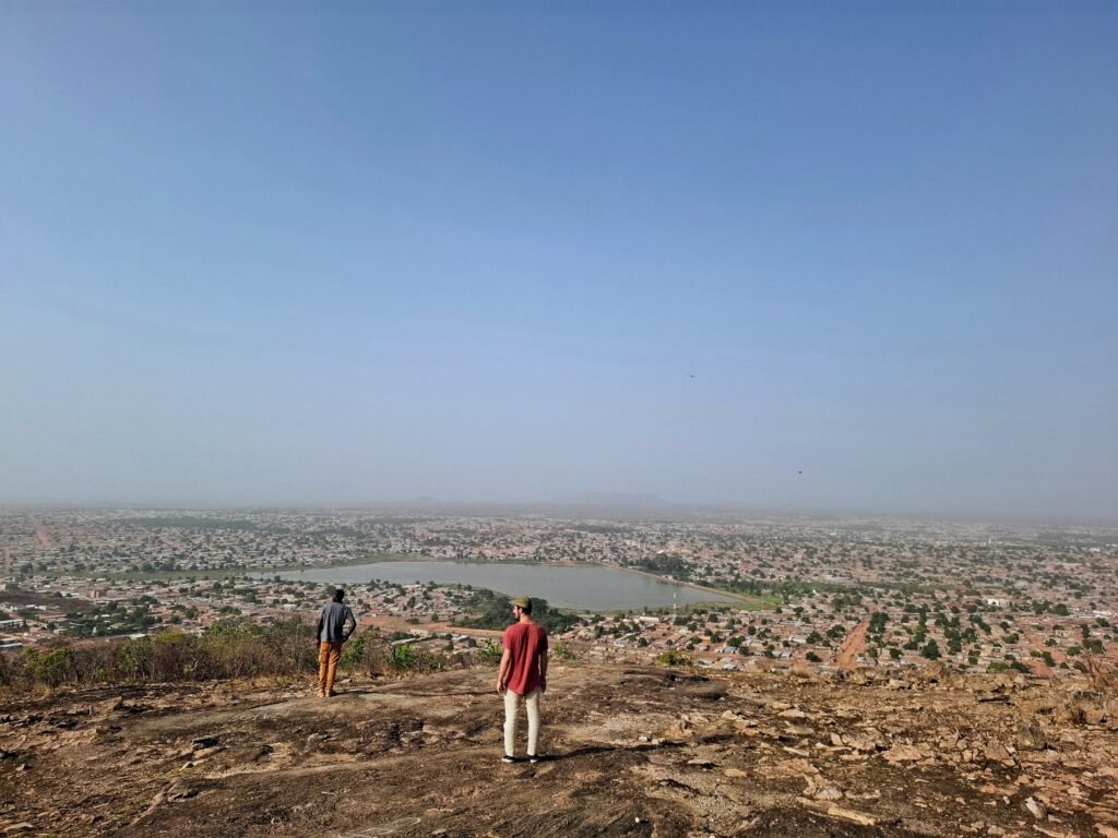 Vue panoramique depuis le sommet du Mont Korhogo, avec notre guide au premier plan, contemplant les paysages étendus du nord ivoirien.