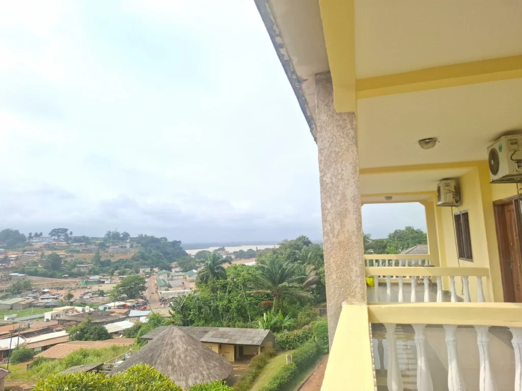 Vue depuis la terrasse de l’Hôtel Le Pollet à Sassandra, avec les collines verdoyantes et les toits de la ville en contrebas.