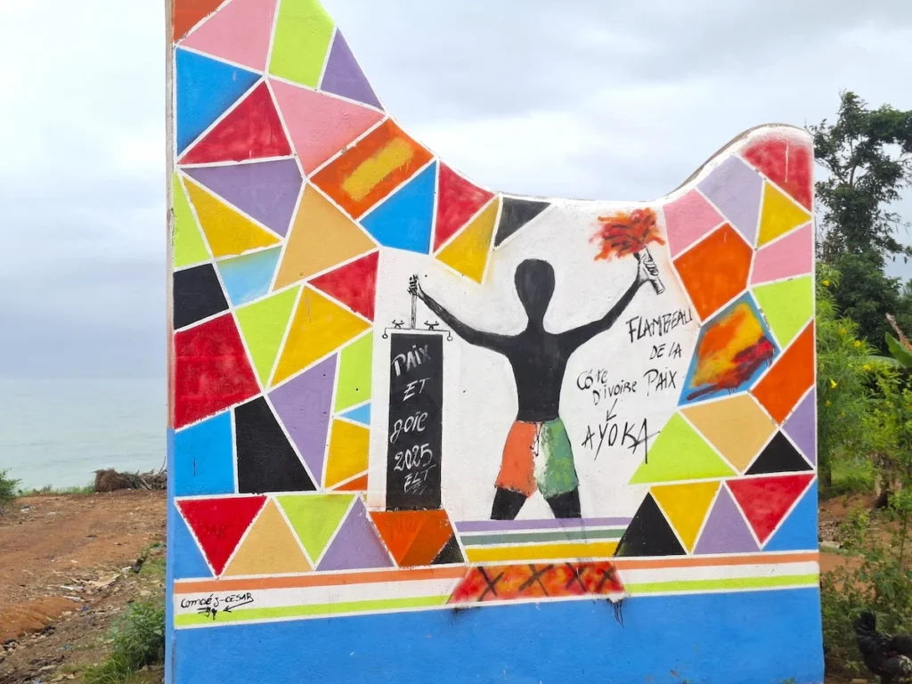 Mur de street art coloré à Sassandra représentant des silhouettes et des motifs géométriques.