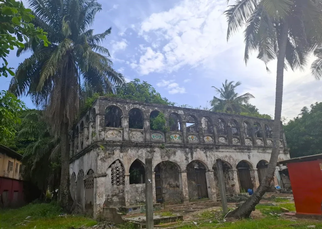 Visiter-Grand-Bassam-Cote-dIvoire-plages-culture-hotel-quartier-france-maison-ganamet Ancien bâtiment colonial du quartier de France à Grand-Bassam entouré de palmiers.