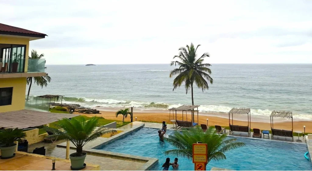 Piscine de l’hôtel Katoum à Grand-Béréby avec vue sur l’océan Atlantique et un palmier en bord de mer.
