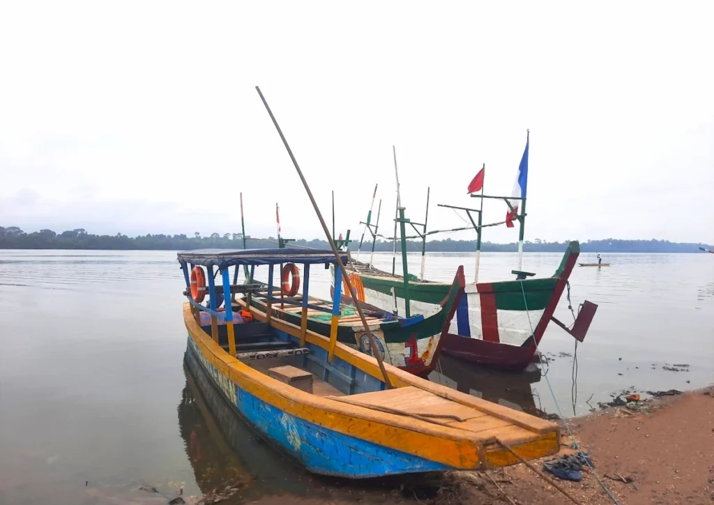 Bateau de pêche coloré amarré sur la lagune à Grand-Lahou, avec des filets visibles. 