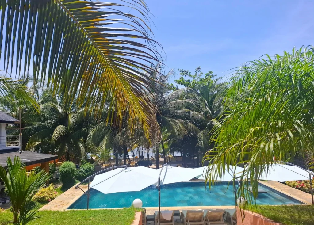 Île-Boulay-Guide-2025-accès-activités-incontournables-que-faire Piscine entourée de palmiers avec vue sur la lagune Ébrié à l’île Boulay.