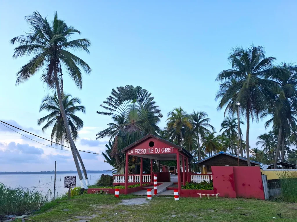 Batiment de l'hotel presqu’île du Christ à Jacqueville, entourée de palmiers et surplombant la plage.