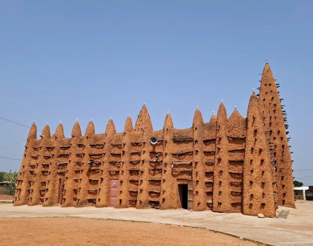 Grande mosquée de Kong en style néo-soudanais, construite en terre crue avec ses tours et contreforts traditionnels sous un ciel bleu.