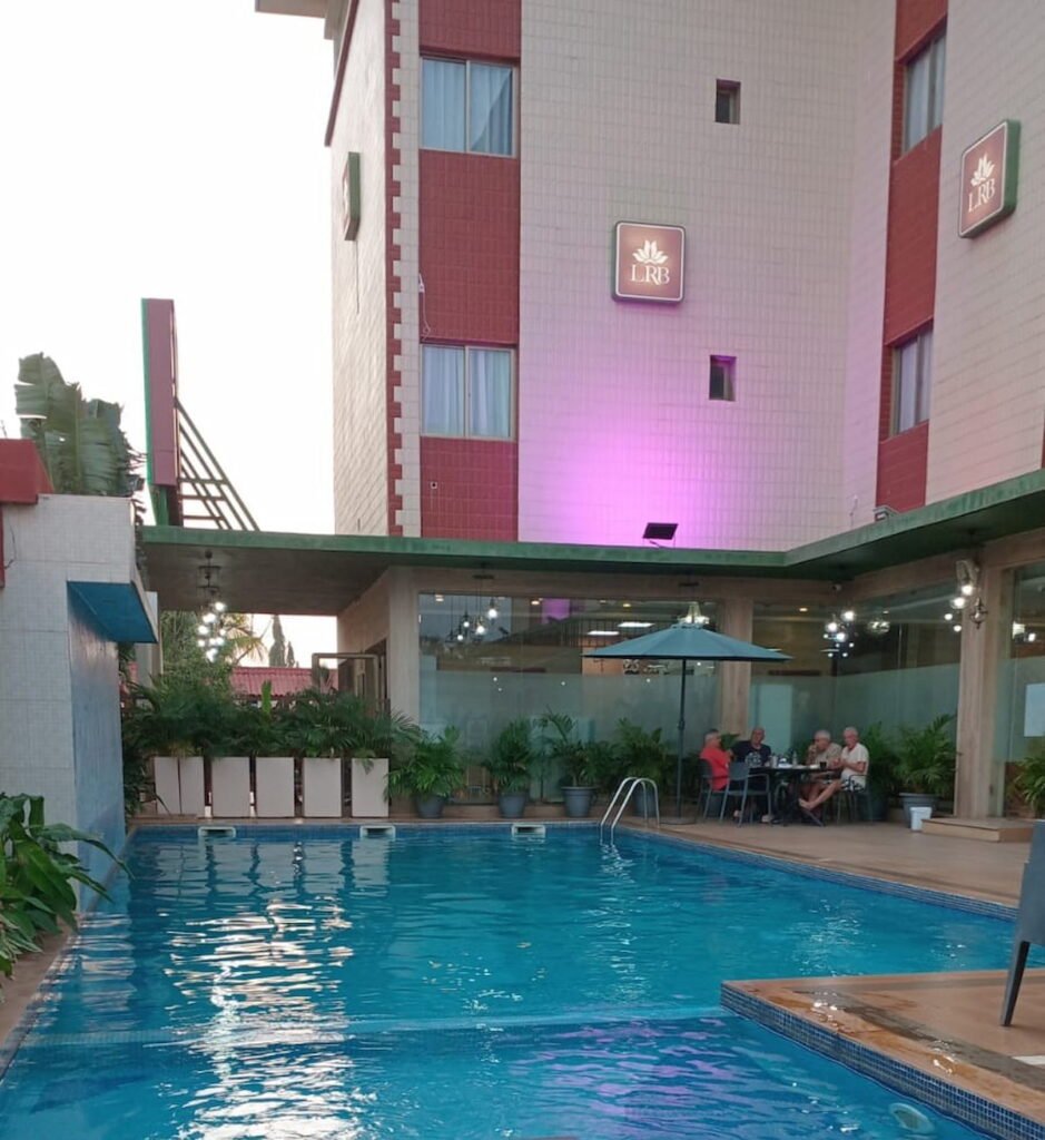 Piscine de l’Hôtel Rose Blanche à Korhogo, éclairée en soirée avec éclairages colorés et architecture moderne. 