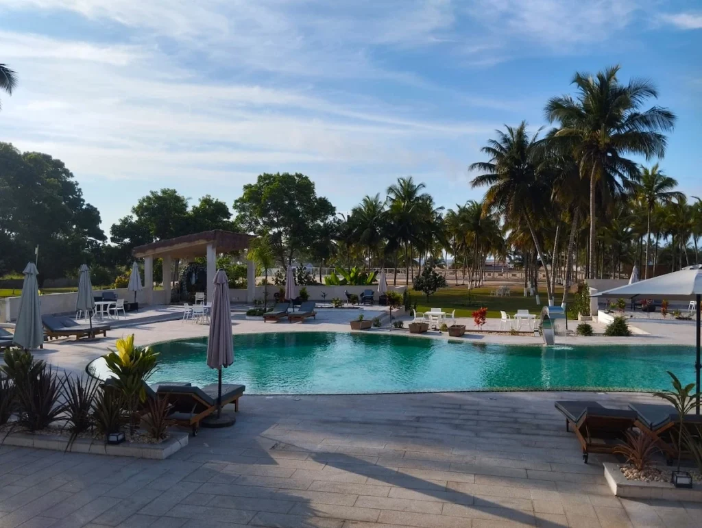 Piscine de l’hôtel Enotel à San Pedro en Côte d’Ivoire, entourée de palmiers et éclairée par un ciel ensoleillé. 