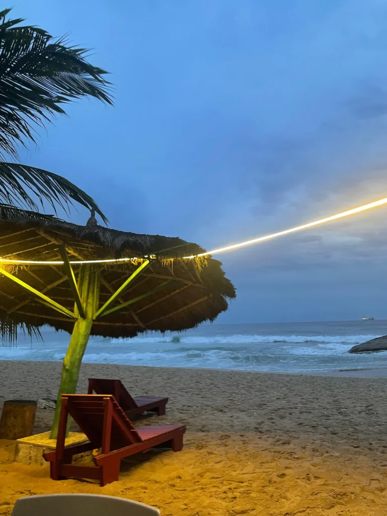 Plage du Palm Rock Hotel à San Pedro au coucher du soleil, avec transats, palmiers et vue sur les vagues de l’océan Atlantique. 