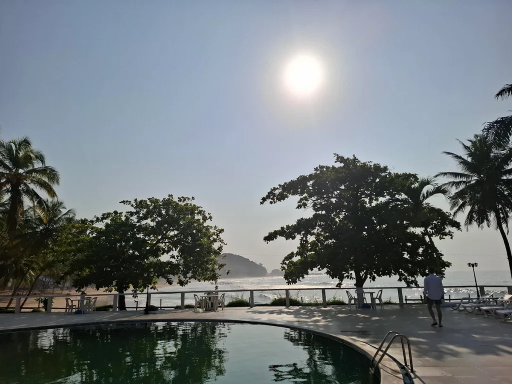 Piscine de l’Hôtel Sophia à San Pedro au coucher du soleil, entourée de palmiers et éclairée par une lumière dorée. 