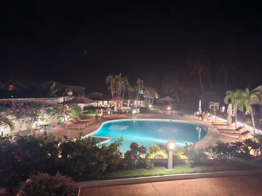 Piscine de l’hôtel Les Jardins d’Ivoire à San Pedro illuminée de nuit, entourée de jardins tropicaux. 