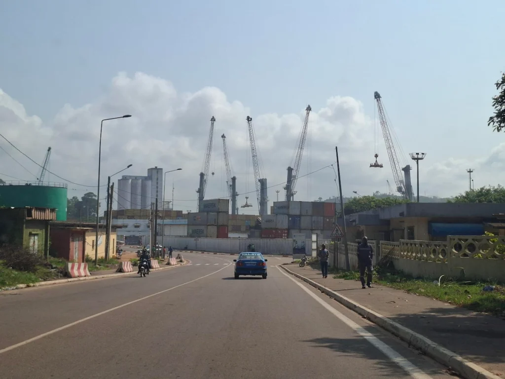 Entrée du port de San Pedro en Côte d’Ivoire, avec grues portuaires et installations industrielles sous un ciel clair. 