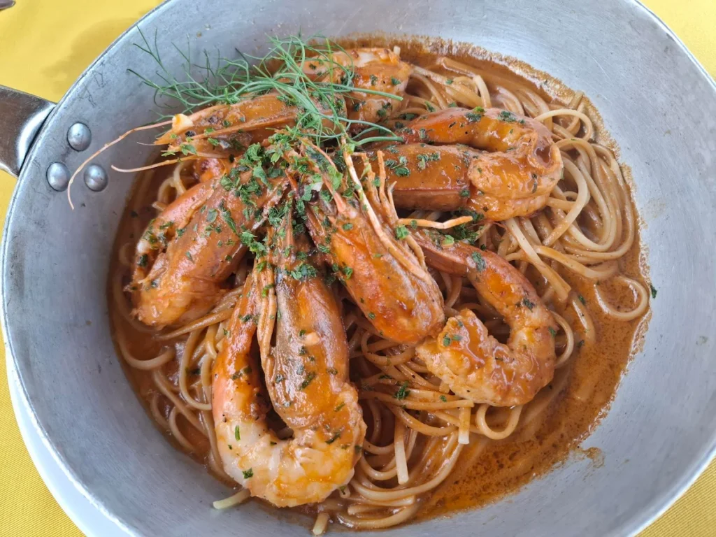 Assiette de pâtes aux fruits de mer avec crevettes et sauce, servie dans un bol. 