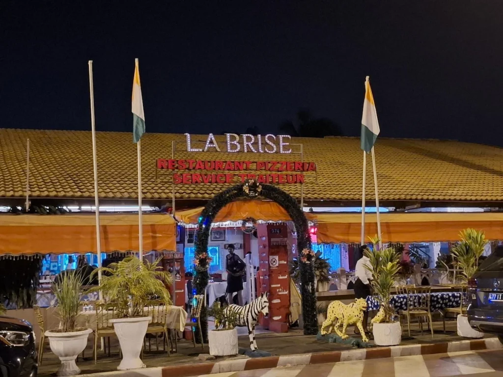 Entrée du restaurant La Brise avec drapeaux et plantes