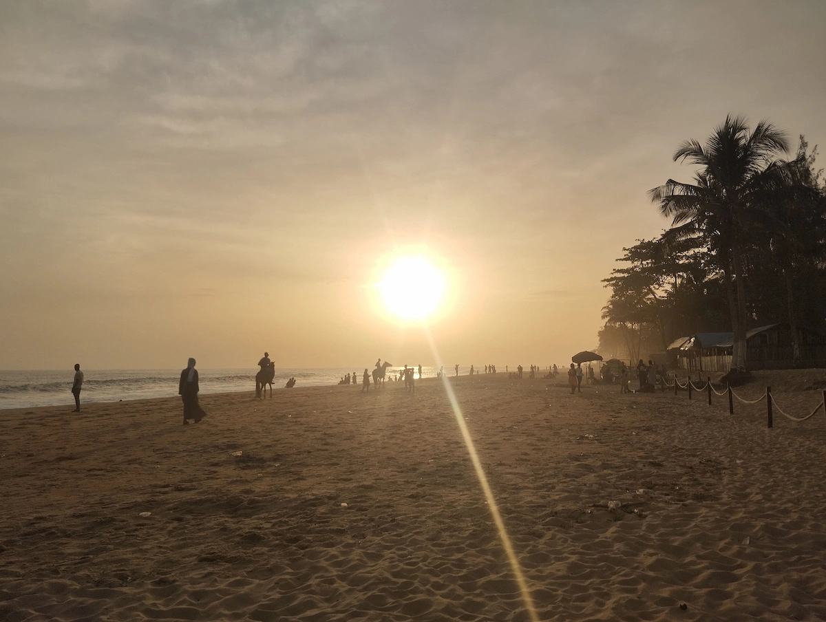 Coucher de soleil sur la plage de Grand-Bassam bordée de cocotiers en Côte d'Ivoire